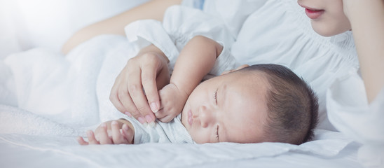 Wall Mural - Portrait of beautiful young asian mother with her newborn baby hands holding, copy space with bed in the hospital. Healthcare and medical family love lifestyle nursery together mother’s day