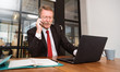 © paulaphoto - Portrait of confident success senior businessman sitting in the office talking on smartphone . Elderly entrepreneur man working with laptop. Business management technology concept