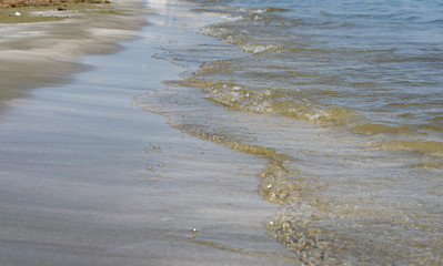 Close-up of sea shore edge and sand  with clear water waves .