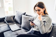 © Miljan Živković - Young woman using smart phone mobile at home, text message sending communication reading mail social network app