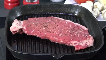 Sticker - Placing a rib steak on a cast iron grill to cook