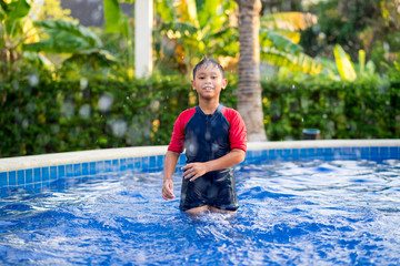 Happy asian kid boy swiming on swiming pool in the summer