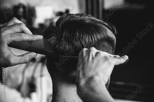Photo Young handsome barber making haircut for attractive bearded man at barbershop