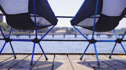 Two empty chairs on the pier at the sea