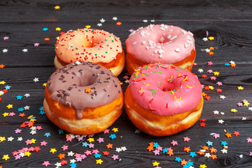 Poster - Assortment of colorful donuts decorated with colorful confetti sprinkles on dark wooden background