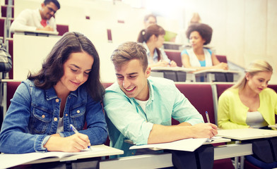 Poster - education, high school, university, learning and people concept - group of international students with notebooks writing at lecture hall