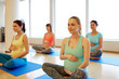 © Syda Productions - pregnancy, fitness and healthy lifestyle concept - group of happy pregnant women exercising in lotus pose at gym yoga