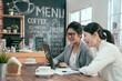 © PR Image Factory - Two young asian female colleagues at coffee shop. businesswomen in suit using tablet computer with documents working in  morning in cafe. office ladies coworker taking break relaxing talking smiling.