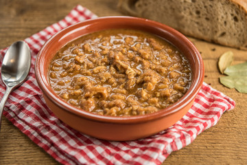 Wall Mural - tripe stew sauce in brown ceramic pot on a wood table 