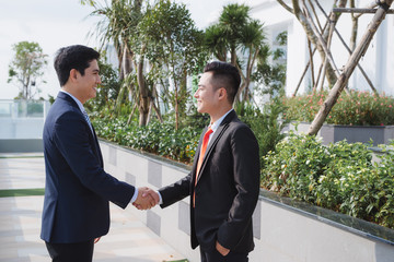 two handsome businessmen greeting each other in the street