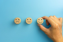 Customer Service Evaluation And Satisfaction Survey Concepts. The Client's Hand Picked The Happy Face Smile Face Icon On Wooden Cube On Blue Background. Copy Space