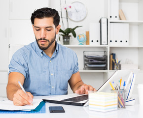 Spanish man is working with documents in laptop