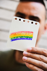 Sticker - man with a rainbow flag in a piece of paper