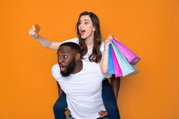 Funny interracial couple in white T-shirts posing for camera in studio