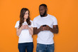 © Yakobchuk Olena - Mistrustful interracial couple in white T-shirts holding smartphones in arms