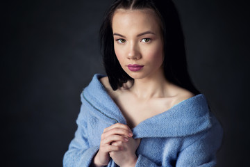 beautiful woman with brunette hair in blue clothes posing on dark background in studio