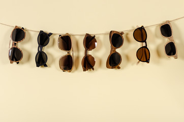 Wooden sunglasses of different design on yellow background. Copy space for text. Sunglasses sale concept. For banner optic shop