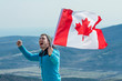 © Danny_Houston87 - A young man in a blue sweater and hat holds a Canadian flag in his hand. A person experiences happiness and a sense of pride. He stands against the backdrop of mountains and sky.