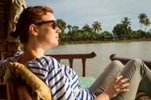 Side View Of Attractive Young Woman Looking Away While Resting On Comfortable Lounger On Terrace Near Calm Sea In India