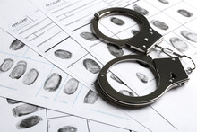 Handcuffs And Fingerprint Record Sheets, Closeup. Criminal Investigation