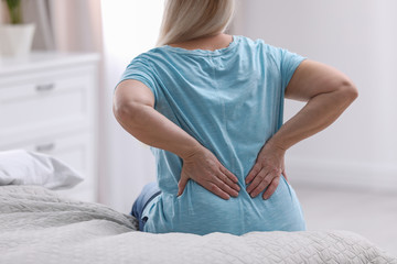 Wall Mural - Senior woman suffering from back pain at home, closeup