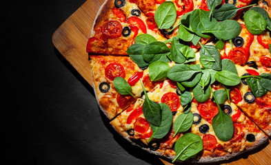 Pizza with Mozzarella cheese, Tomatoes, pepper, olive, Spices and Fresh spinach. Italian pizza. Pizza Margherita or Margarita on Dark grey black slate background