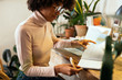 © Bonninstudio/Stocksy - Afro businesswoman working in office full of plants.