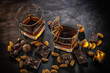 Glasses of whiskey, chocolate with hazelnuts, candy and almonds on a dark wooden background.