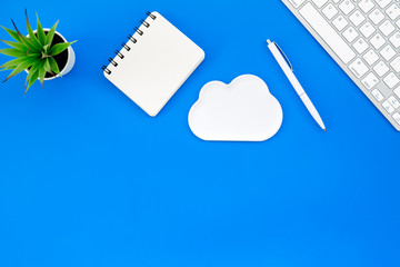 cloud service concept with clouds, notebook, plant and keyboard on blue background top view mockup