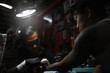© Santi Nunez/Stocksy - Professional asian tattooer makes a tattoo.