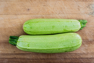 Tabla de madera con dos calabacines verdes.