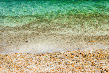 Poster - Soft waves with foam of water on pebbles and sandy beach.