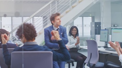 Poster - Young Cheerful Handsome Business Manager Wearing a Suit and Tie Dancing in the Office. Diverse and Motivated Business People Work on Computers in Modern Open Office.