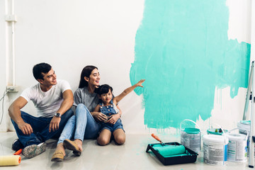 Wall Mural - Happy family using a paint roller and painting walls in their new home