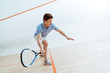 Emotional sportsman in blue polo shirt playing squash in four-walled court