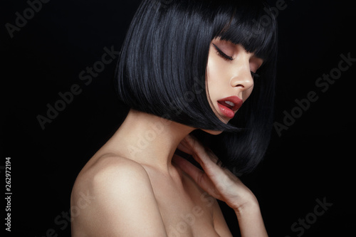 Fotomural Profile portrait of a sensual young woman in black wig, bob haircuts, she touches his neck, have closed eyes, make up, big lips, naked shoulders, isolated on a black background