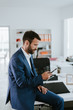 © JustLife - Manager on his phone. Man at work sitting on a desk while talking on the phone.