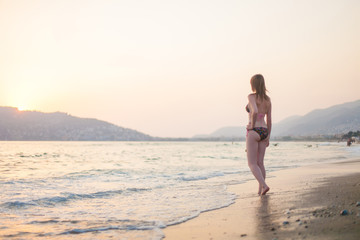 Wall Mural - Summer woman bikini vacations concept. Outdoor lifestyle portrait of beautiful girl in swimsuit. Happy Carefree Woman Enjoying Beautiful Sunset on the Beach