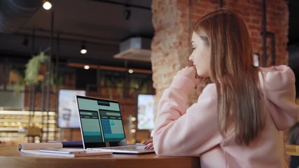 Wall Mural - Tilt down side view of freelance female website designer creating design templates for different devices on laptop sitting at table in cafe (ATTN templates designed by ME)