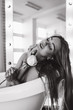 © dimadasha - Photo session of a young girl in a bathroom with a white rose in her hand.