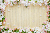 Fototapeta Nowy Jork - Frame of spring flowers of sakura on bamboo background. Beautiful cherry blossom sakura in springtime