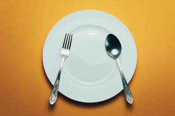 Poster - White bowl and a fork with a spoon on an orange background