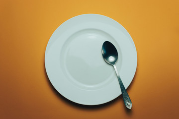 Poster - White bowl and a fork with a spoon on an orange background