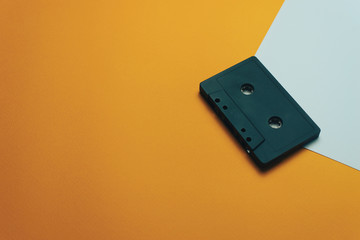 Poster - Black classic magnetic cassette tape on a orange background.