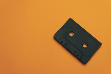 Poster - Black classic magnetic cassette tape on a orange background.
