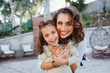 © Cavan for Adobe - Portrait of happy mother embracing cute daughter while standing in yard