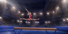 Female Athlete Doing A Complicated Exciting Trick On Gymnastics Balance Beam In A Professional Gym. Girl Perform Stunt In Bright Sports Clothes