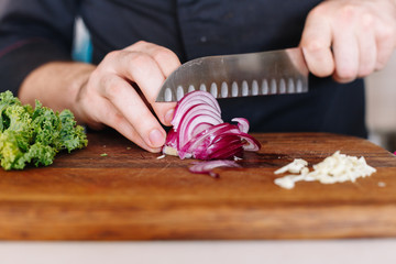 Chef cut onion and vegetables. Wooden. Kitchen. Healthy food. Raw.