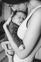 Young mother, holding tenderly her newborn baby girl, close portrait