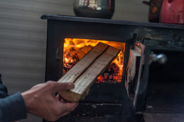 Wall Mural - Man putting log to wood burning stove